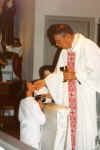 Father Wickens administers Holy Communion to a young man for the first time